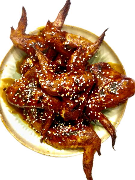 Platter of golden, crispy pellet-smoked wings drizzled with a sticky garlic honey maple buffalo sauce.