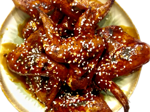 Platter of golden, crispy pellet-smoked wings drizzled with a sticky garlic honey maple buffalo sauce.