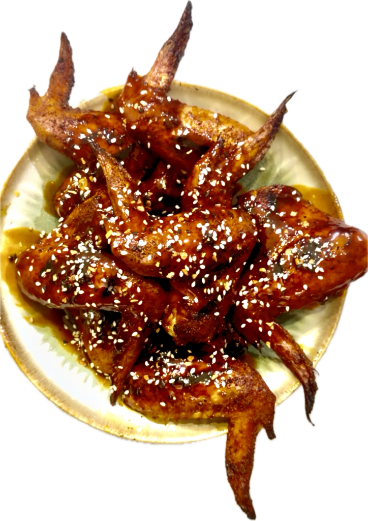 Platter of golden, crispy pellet-smoked wings drizzled with a sticky garlic honey maple buffalo sauce.